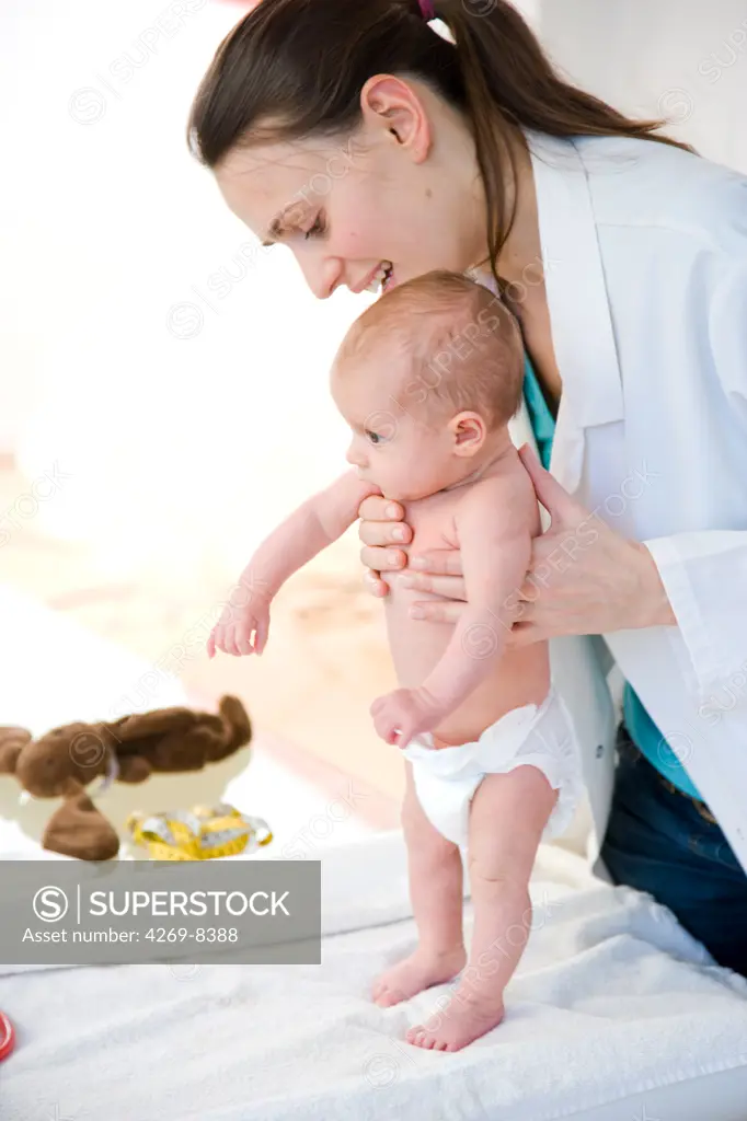 2 months old baby medical examination. The pediatrician is holding the baby during a test for the stepping or walking reflex.