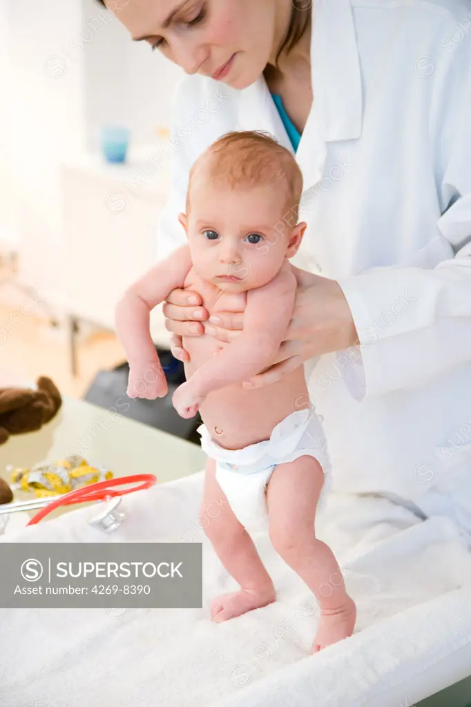 2 months old baby medical examination. The pediatrician is holding the baby during a test for the stepping or walking reflex.