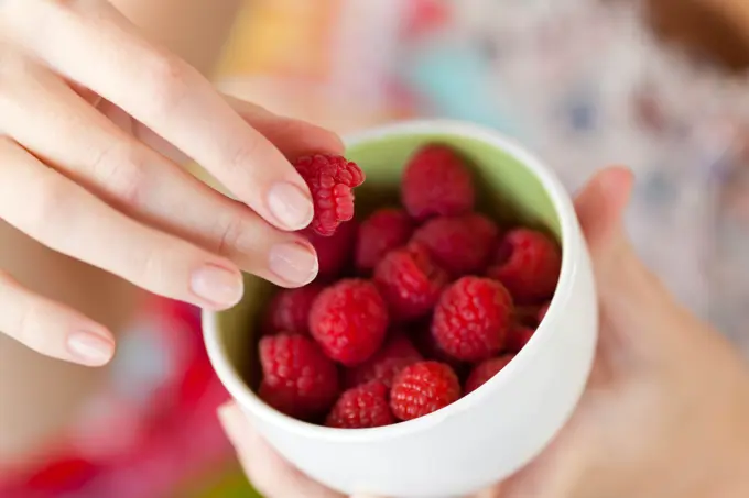 Food. Woman eating raspberries.