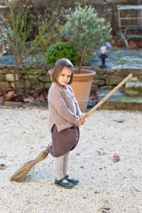 4 year old girl playing the witch on a broom.