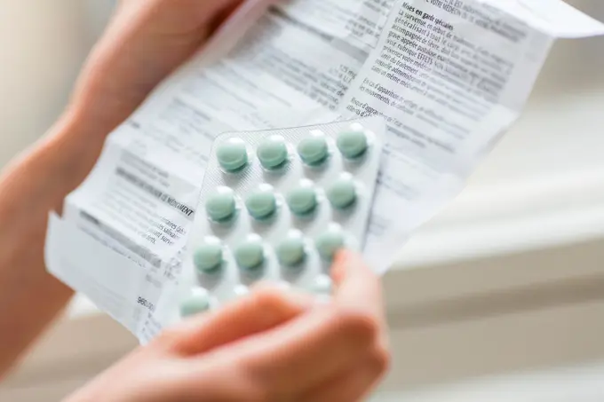 Medicine, Woman reading medicine instruction sheet.