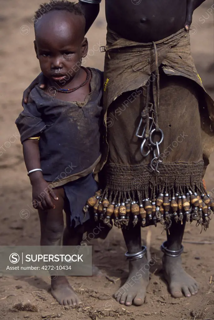 A young Dassanech girl holds her little brother.  She wears a leather skirt with an elaborate fringe of wooden and metal tassles.  Much the largest of the tribes in the Omo Valley numbering around 50,000, the Dassanech (also known as the Galeb, Changila or Merille) are Nilotic pastoralists and agriculturalists.