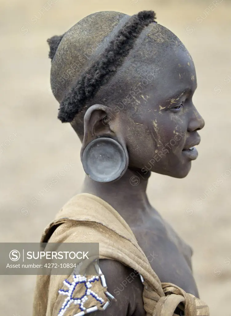 The typical hairstyle of a young Mursi girl. The Mursi speak a Nilotic language and have affinities with the Shilluk and Anuak of eastern Sudan.  They live in a remote area of southwest Ethiopia along the Omo River.