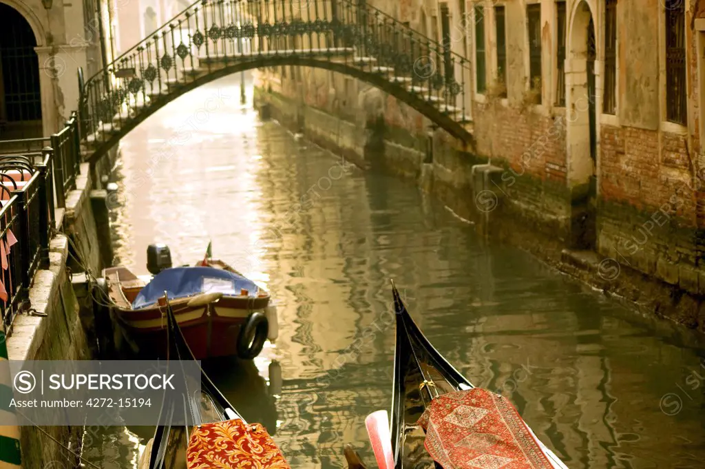 Italy, Veneto, Venice; Two gondolas tied up in a typically misty atmosphere with a bridge and the Gran Canal in the background