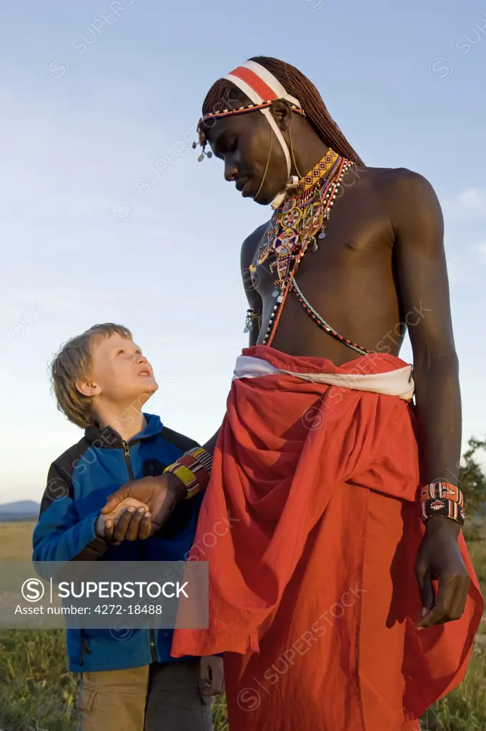 Kenya, Laikipia, Lewa Downs.  A young boy on a family safari with one of the Laikipiak Maasai guides. (MR)