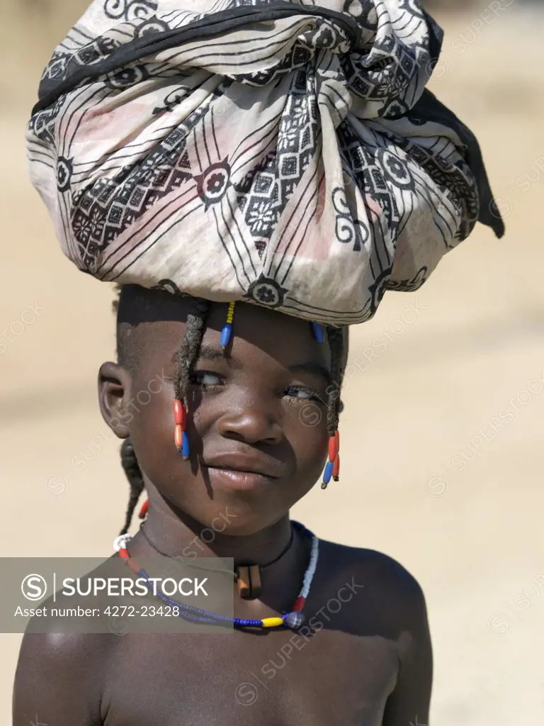 A young Himba girl at Opuwo, an important administrative centre of the Himba. Her hair is plaited in the traditional Himba way. The Himba are Herero-speaking Bantu nomads who live in the harsh, dry but starkly beautiful landscape of remote northwest Namibia.