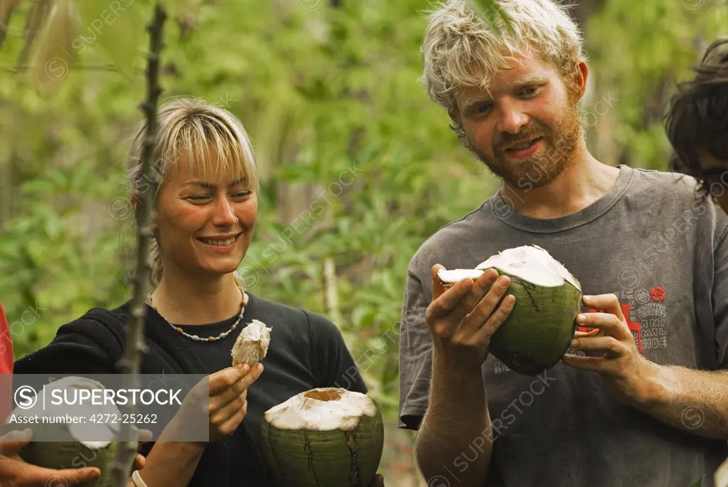 South Pacific, Fiji, Kadavu. Conservation volunteers eating fresh coconut on Dravuni Island