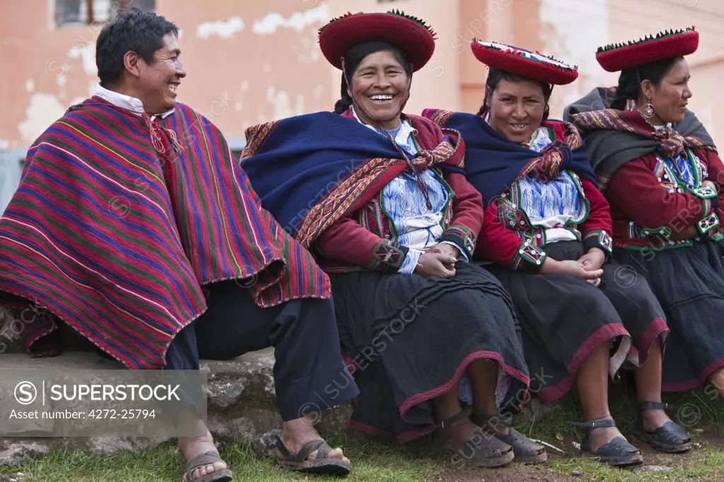 Peru, A man shares a joke with a group of native Indian women in traditional costume. Their saucer-shaped hats, beautifully decorated red jackets, black skirts and hand-woven woollen blankets round their shoulders are typical of the region.