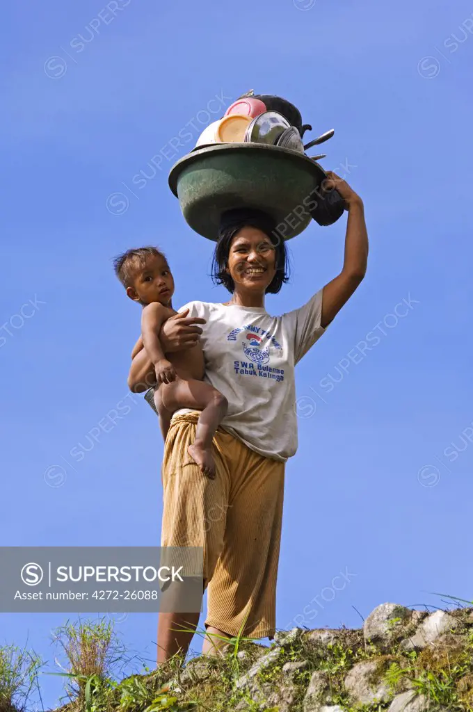 Philippines, Luzon Island, The Cordillera Mountains, Kalinga Province, Tinglayan. Mother and baby carrying dishes in Dananao village.