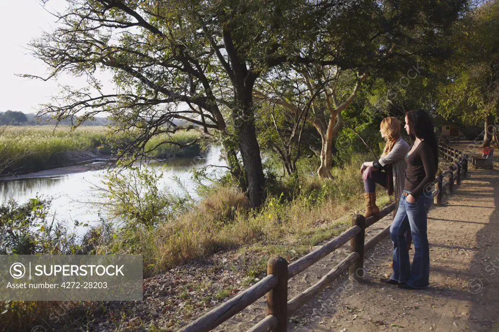 Women looking across river, Kruger National Park, Mpumalanga, South Africa (MR)