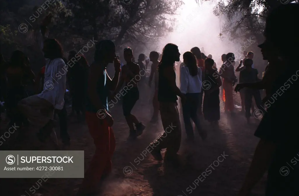 Dance floor at Trance party backlit through trees