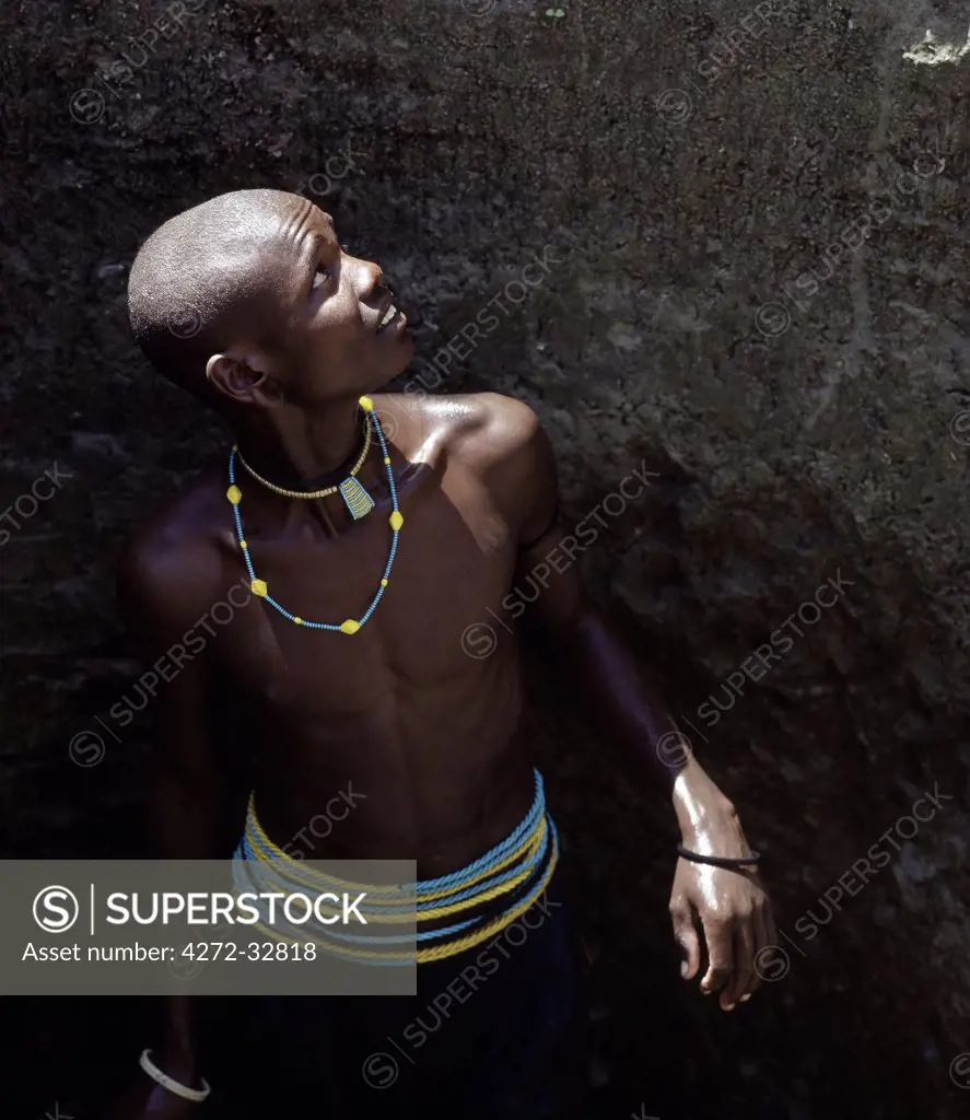 A young Datoga man helps to draw water for his family's livestock from a well on the east side of Lake Manyara. All young men wear strings of twisted yellow and light blue beads round their waists. The Datoga (known to their Maasai neighbours as the Mang'ati and to the Iraqw as Babaraig) live in northern Tanzania and are primarily pastoralists.