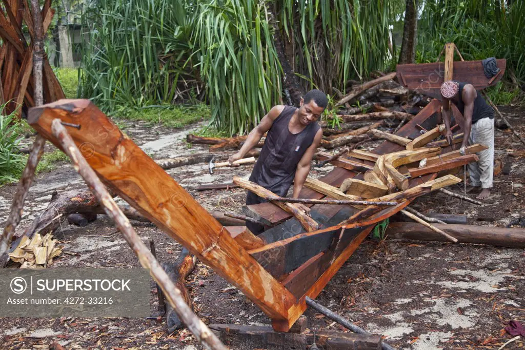 Tanzania, Zanzibar. Craftsmen build a dau, a wooden sailing boat commonly called a dhow, on Nungwi beach at the northern tip of Zanzibar Island. The hardwood is brought from the mainland.