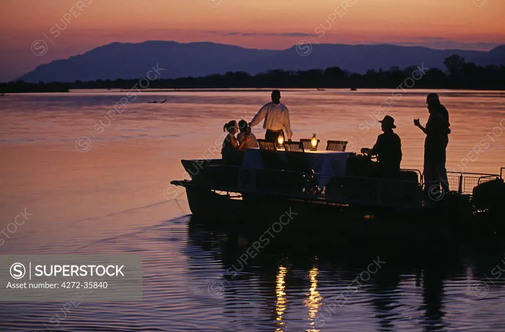 Zambia, Lower Zambesi National Park. Guests enjoying sundowners on a barge on the Zambezi River.