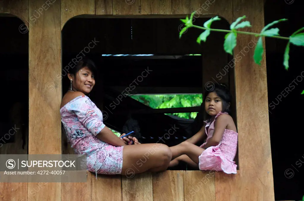 Mother and child sat on window, Ticuna Indian Village of Macedonia, Amazon River, near Puerto Narino, Colombia