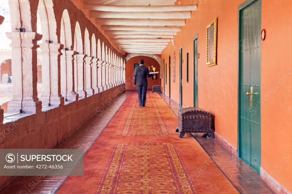 South America, Peru, Cusco, a waiter carrying a tray with a cocktail to a room in the Orient Express Monasterio hotel, housed in a former Spanish convent, MR,, PR,