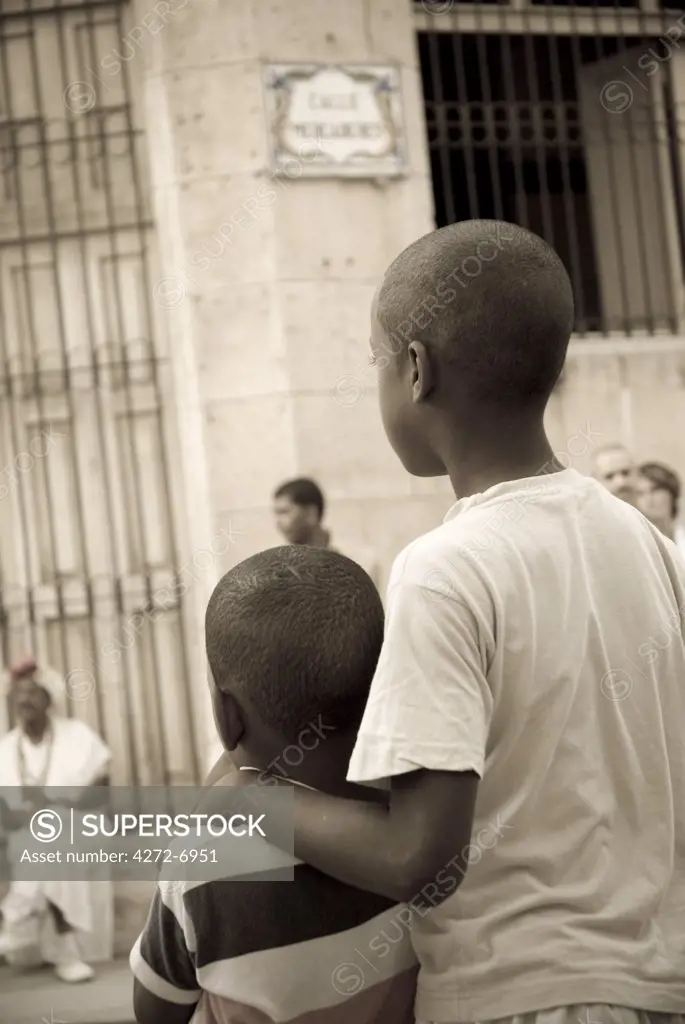 Cuba, Havana. Boys watching impromtu street parade, Plaza Vieja