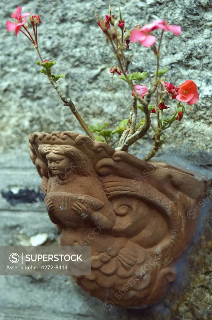 A terracotta flower pot cast in the shape of a mermaid adorns a fisherman's cottage in Mousehole, Cornwall, England