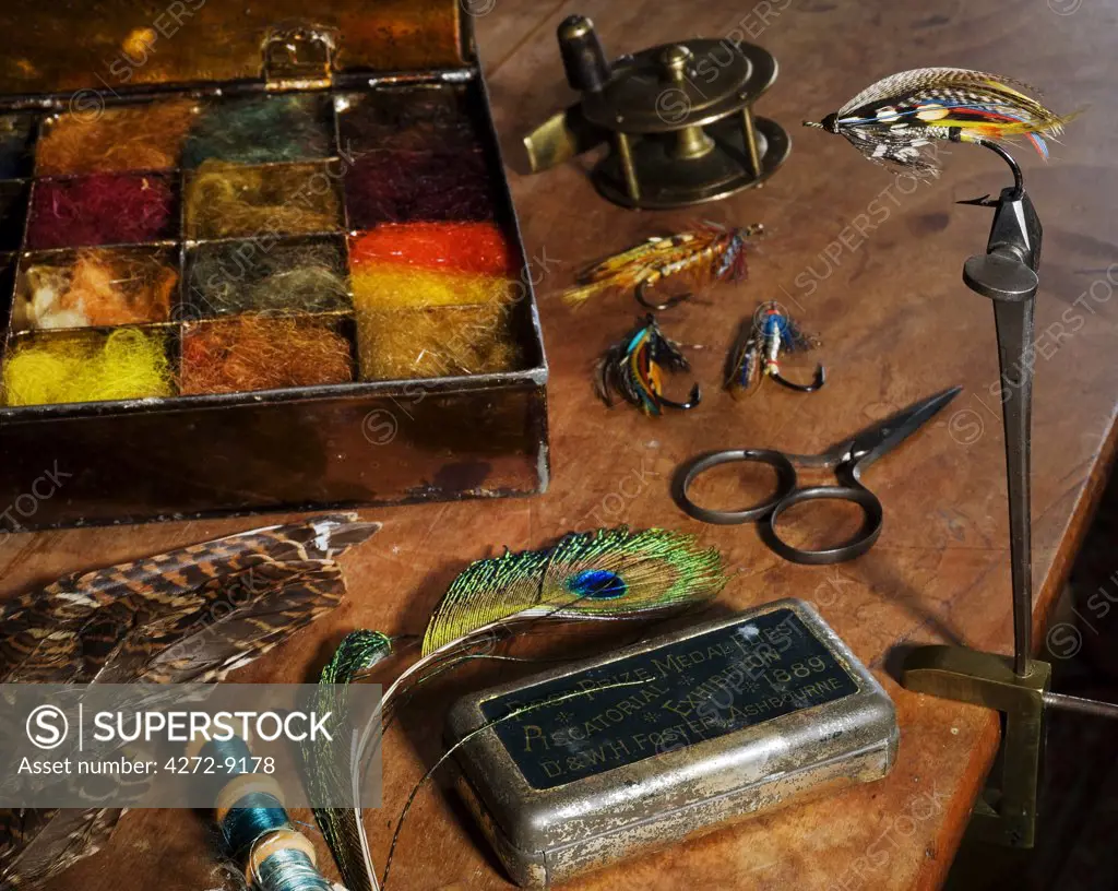 UK.  Antique fly-tying equipment with a traditionally tied salmon fly  in the vice on a fly-tiers bench