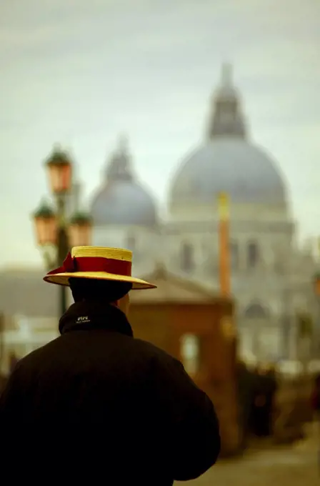 Venice, Veneto, Italy; A gondolier with the church of Santa Maria della Salute in the background