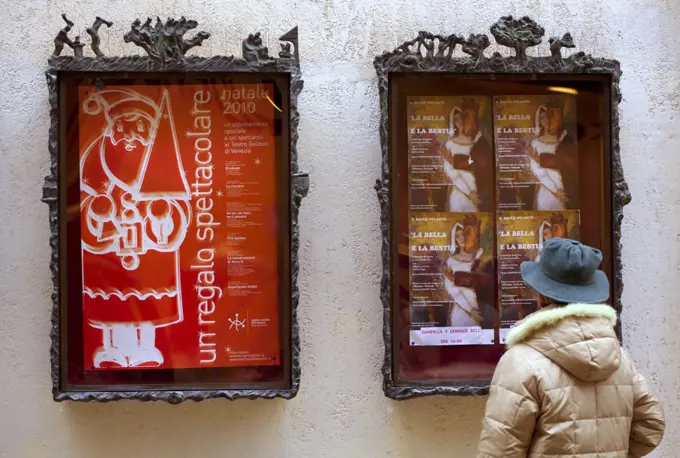 Venice, Veneto, Italy; A passerby looking at the theatre bill