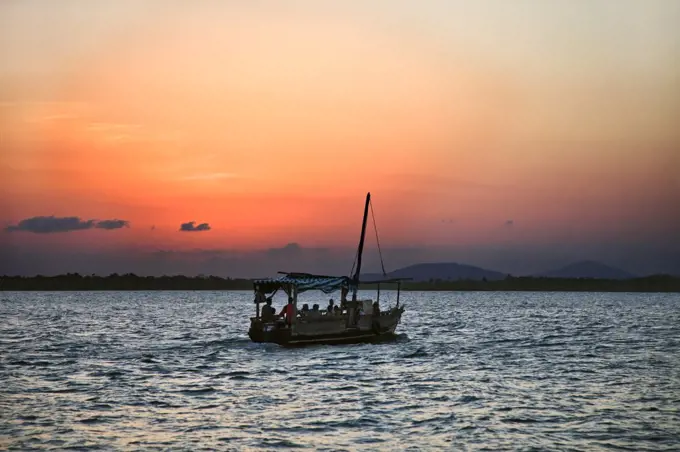 Kenya, Mombasa. As the last rays of the setting sun turn the sky a brilliant red, Residents of Funzi Island, off Kenyas south coast, take the ferry back to the mainland.