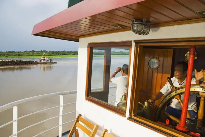 Peru, Amazon, Amazon River. Crew steering the Ayapua Riverboat up the Amazon River.