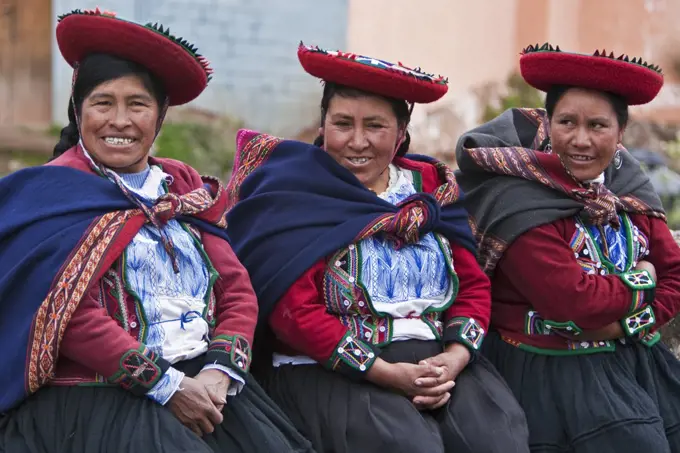 Peru, A group of native Indian women in traditional costume wearing saucer-shaped hats, beautifully decorated red jackets and woollen blankets round their shoulders.