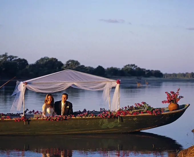 Zambia, South Luangwa National Park, Robin Pope Safaris. Bush wedding at RPS; bride and groom going away in a safari gondola on the Luangwa River.