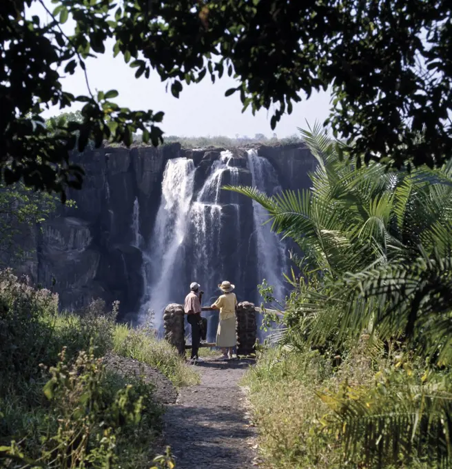 A visitor gazes at the magnificent Victoria Falls. ;The Falls are more than a mile wide and are one of the world's greatest natural wonders. The mighty Zambezi River drops over 300 feet in a thunderous roar with clouds of spray.