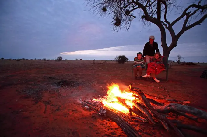 Family gathered around campfire in Tsavo East National Park, Kenya.