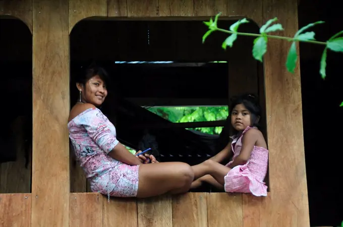 Mother and child sat on window, Ticuna Indian Village of Macedonia, Amazon River, near Puerto Narino, Colombia