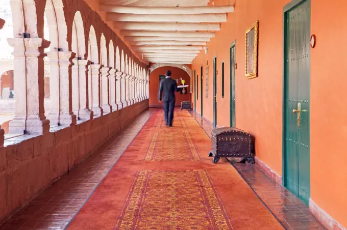 South America, Peru, Cusco, a waiter carrying a tray with a cocktail to a room in the Orient Express Monasterio hotel, housed in a former Spanish convent, MR,, PR,