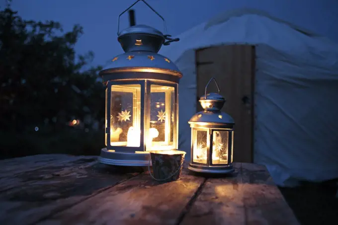 England, Isle of Wight. Candle lanterns on a table with a yurt in the background; Island Yurts near Freshwater Bay.