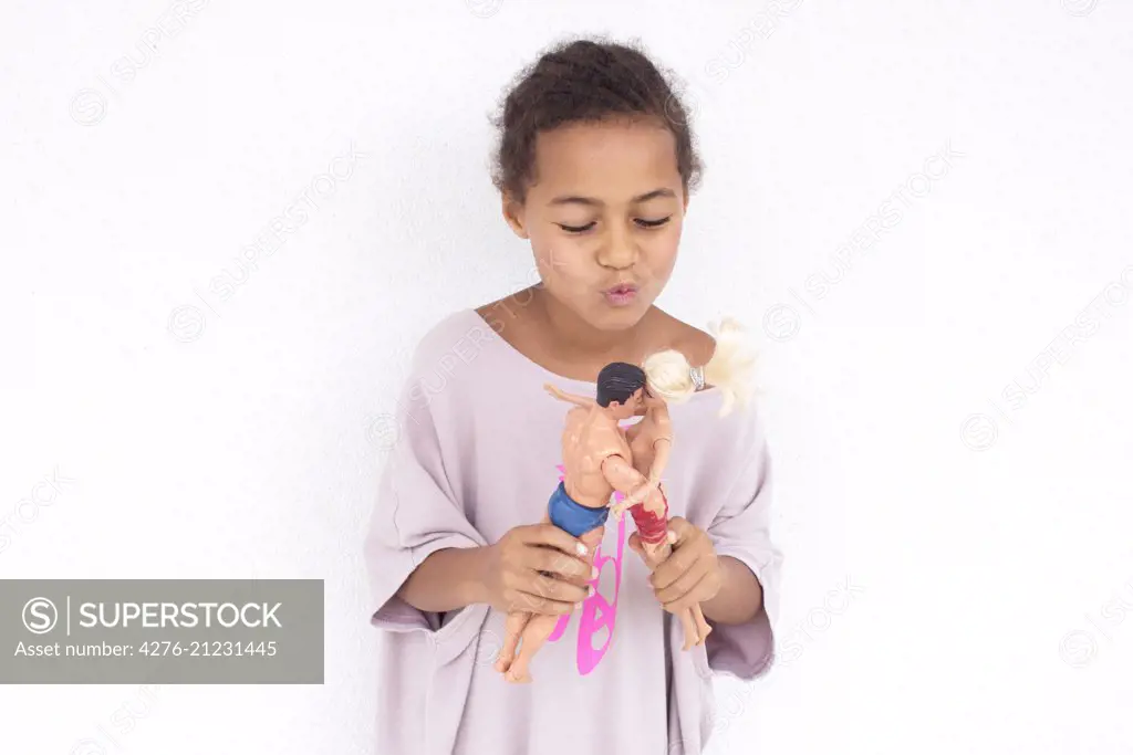 Girl making dolls kiss each other SuperStock