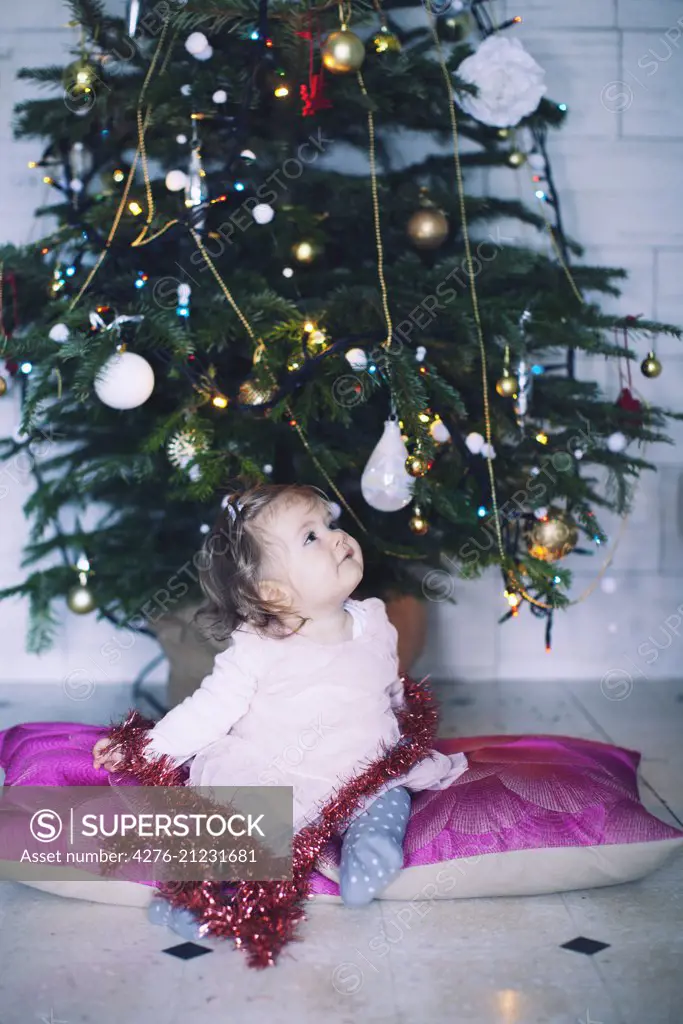 Baby girl sitting in front of Christmas tree