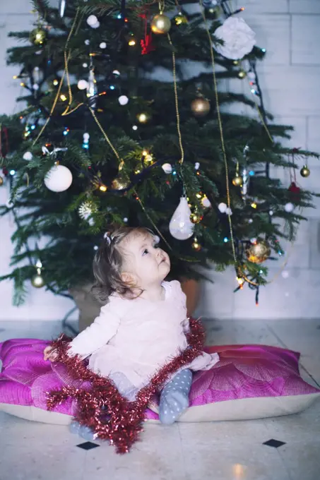 Baby girl sitting in front of Christmas tree