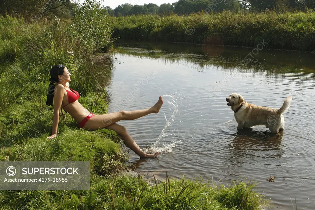 Golden Retriever and young woman playing at the shore