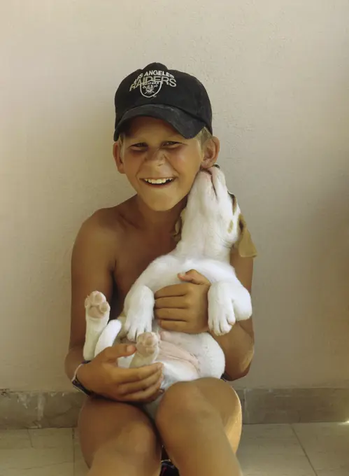 half breed dog - puppy nibbling at a boy's ear