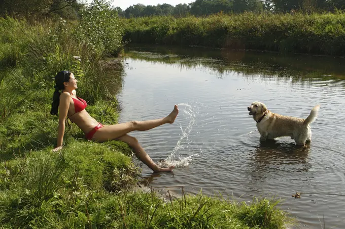 Golden Retriever and young woman playing at the shore