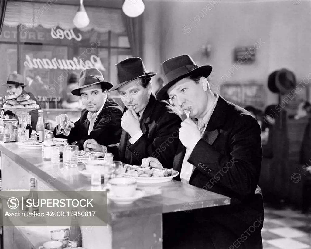 Three men with hats eating at the counter of a diner All persons depicted are not longer living and no estate exists Supplier warranties that there wi...