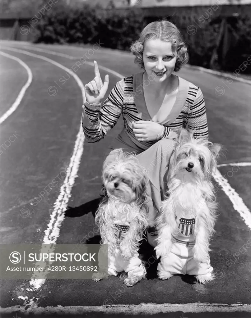 Woman with her two dogs on a race track All persons depicted are not longer living and no estate exists Supplier warranties that there will be no mode...