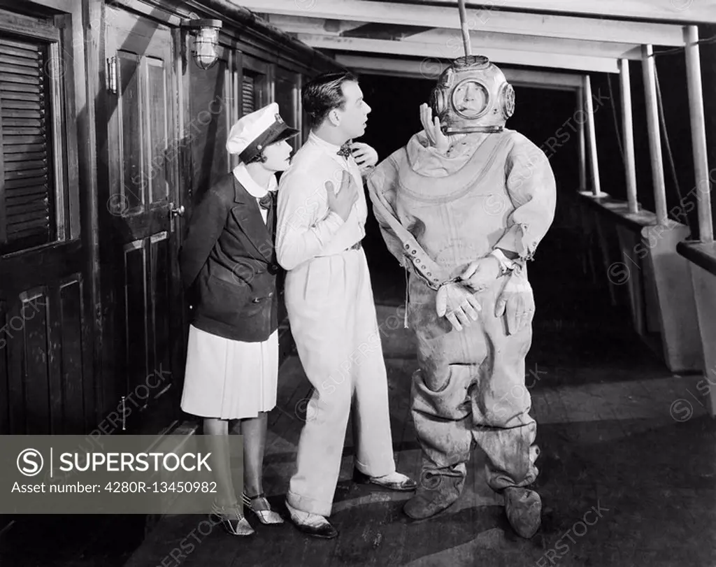 Two people looking in shock at a diver in a divers suit All persons depicted are not longer living and no estate exists Supplier warranties that there...