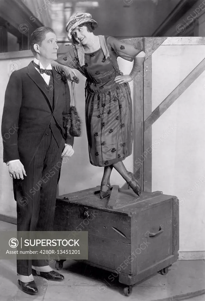 Woman standing on a trunk next to a very tall man All persons depicted are not longer living and no estate exists Supplier warranties that there will ...