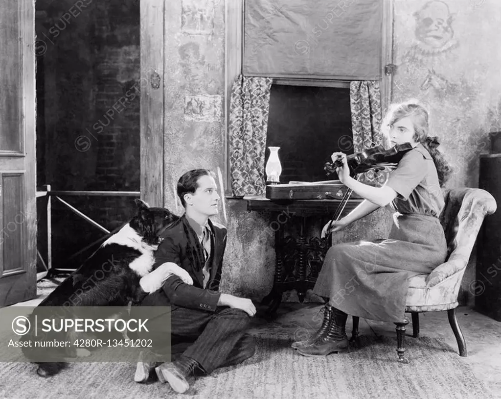 Woman playing the violin for her boyfriend and dog All persons depicted are not longer living and no estate exists Supplier warranties that there will...