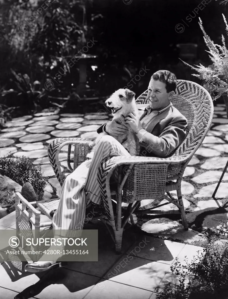 Man sitting in chair outside with dog All persons depicted are not longer living and no estate exists Supplier warranties that there will be no model ...