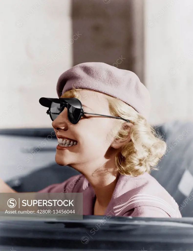 Young woman with a beret and sunglasses in a car, on the go Old Visuals