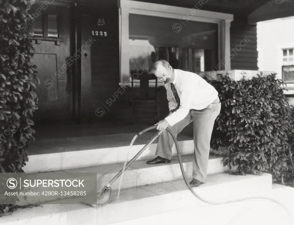 Man moping his front stairs (OLVI008_OU281_F)