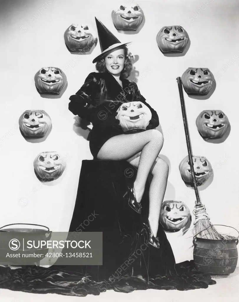 Bewitching woman sitting among carved pumpkins