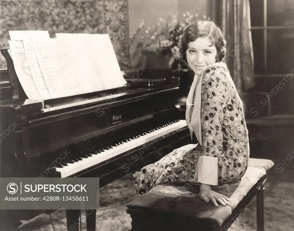 Smiling woman sitting by piano at home